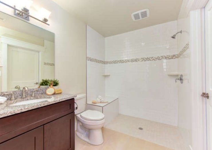 Bright bathroom with dark wood vanity, granite countertop, and double sink, large mirror, and modern light fixture above the mirror.